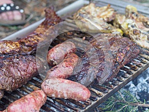 slow grilling chorizo sausages , chicken quarters, skirt and flank muscle steaks argentinian cuts photo