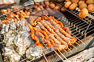 Grilling food, bbq, barbecue. Grilled tasty sausage with the addition of herbs and vegetables cooking on flaming grill