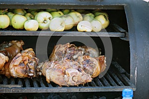 Grilling food. The meat is barbecued with coals. Pork knuckle with apples on the barbecue.