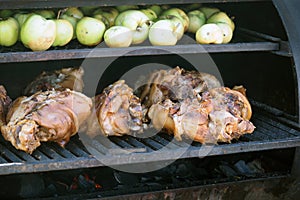 Grilling food. The meat is barbecued with coals. Pork knuckle with apples on the barbecue.