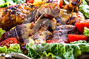 Grilling. Grilled chicken. Grilled chicken legs. Grilled chicken legs, lettuce and cherry tomatoes. Traditional cuisine.