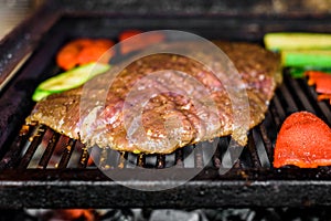 Grilling marinated angus beef flank steak on hot coals barbecue grill