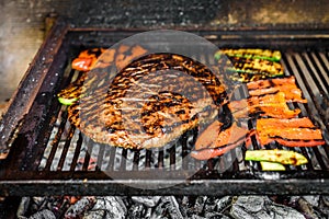 Grilling marinated angus beef flank steak on hot coals barbecue grill