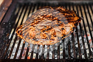 Grilling marinated angus beef flank steak on hot coals barbecue grill