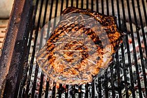 Grilling marinated angus beef flank steak on hot coals barbecue grill