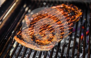 Grilling marinated beef flank steak on hot coals barbecue grill