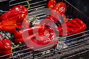 Grilling Process of preparing red bell pepper on barbecue bbq grill. Flaming fire, ember charcoal and smoke. Close up Whole street