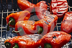 Grilling Process of preparing red bell pepper on barbecue bbq grill. Flaming fire, ember charcoal and smoke. Close up Whole street