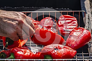 Grilling Process of preparing red bell pepper on barbecue bbq grill. Flaming fire, ember charcoal and smoke. Close up Whole street