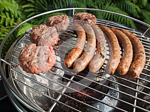 Grilling sausages and beefburgers on a barbecue