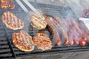 Grilling sausages, burgers, pork steak on barbecues gas grill for party. Hot dogs,sausages and hamburgers on a barbeque, bbq. Smok