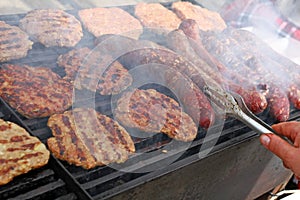 Grilling sausages, burgers, pork steak on barbecues gas grill for party. Hot dogs,sausages and hamburgers on a barbeque, bbq. Smok