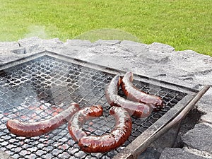 Grilling sausages on the grill. Frying food on charcoal and on fire. Fatty food. Calories and energy for muscles. Picnic on the st