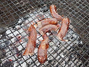 Grilling sausages on the grill. Frying food on charcoal and on fire. Fatty food. Calories and energy for muscles. Picnic on the st