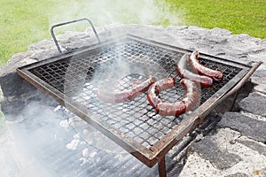 Grilling sausages on the grill. Frying food on charcoal and on fire. Fatty food. Calories and energy for muscles. Picnic on the st