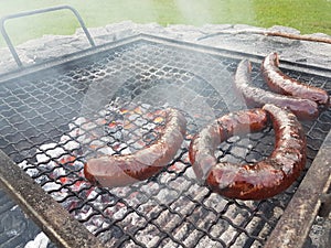 Grilling sausages on the grill. Frying food on charcoal and on fire. Fatty food. Calories and energy for muscles. Picnic on the st