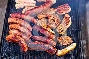 Grilling sausages and pork chops on barbecue grill. BBQ in the garden