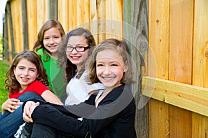 Grils group in a row smiling in a wooden fence