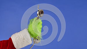 The Grinch's green haired hand holds an antique telephone receiver on a blue isolated background. Gift Snatcher