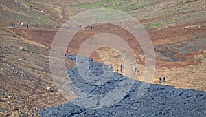 A unique natural attraction. People are walking over the new lavafield of the volcano eruption
