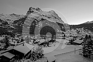 Grindelwald village at dusk with Mt. Eiger peak, snow covered landscape in winter, black white photography, Switzerland