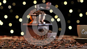 Grinder filled with coffee beans and cup on a saucer