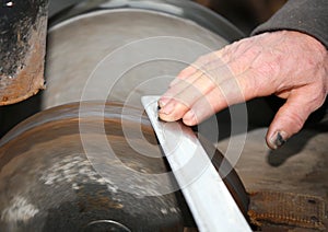 Grinder with large hands sharpen a blade photo