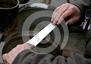 Grinder with large hands sharpen a knife