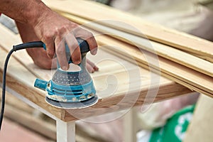 Grinder worker polishes a wooden board. Sanding boards Orbital eccentric machine.