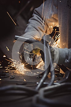Grinding loops of steel pipe with many sparks on a work table