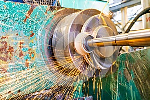 Grinding metal, abrasive wheel at high speeds removes part of the metal on the machined surface of a round part