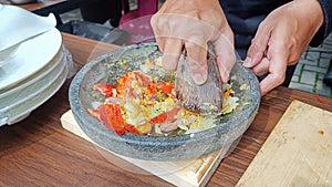 Grinding the spices with a mortar and pestle from a stone on a wooden table