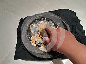 Grinding spices using a stone mortar by hand