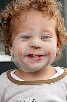 Grinning 2 yr old blond boy who lost a front tooth photo
