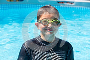 Grinning boy in swim shirt and goggles at pool