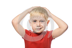 Grinning, fair-haired boy in a red t-shirt folded his arms behind his head. Isolate on white background