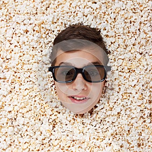 Grinning, flaunt young boy in stereo glasses looking out of popcorn
