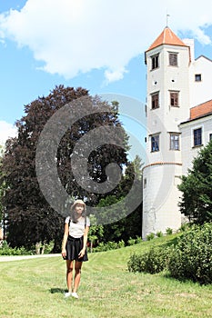 Grinning girl in front of tower of castle in Telc