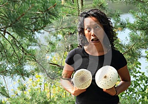 Grinning girl holding parasol mushrooms in front of chest