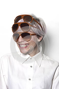 Grinning girl wearing three pairs of sunglasses