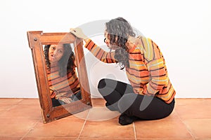 Grinning ropical girl watching herself in mirror