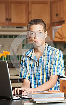 Grinning teen with laptop and textbooks