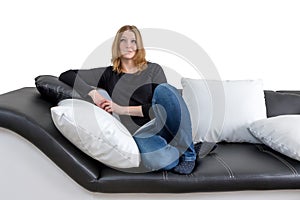 Grinning young woman is sitting on a black and white couch