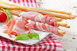 Grissini bread sticks with ham, tomato and basil
