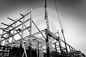 Gritty construction image of steel framing and construction crane on building site in monochrome