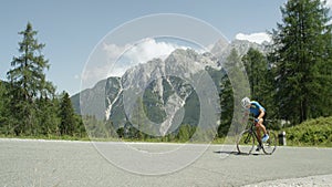 Gritty mountain biker pedaling up a steep mountain on a sunny summer afternoon.