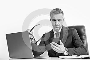 grizzled businessman with eyewear using phone in office with computer