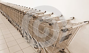 Grocery carts in a row against a white wall. Parking of grocery carts Sepia Color. Vintage Style