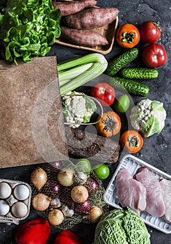 Grocery concept. Paper bag with fresh organic vegetables, fruits, turkey meat on a dark background, top view. Healthy diet food