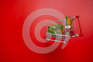 grocery consumer basket.Rising food prices.Shopping cart with groceries on a red background.Vegetables and fruits price